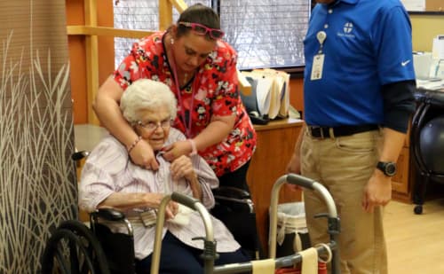 Nurse assisting elderly patient with sweater