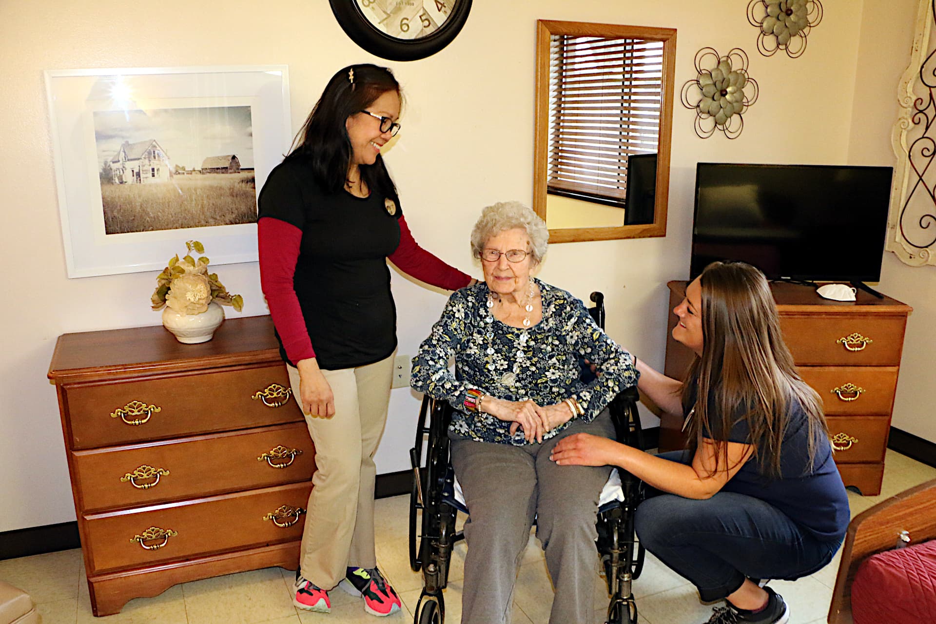 Two nurses speaking with an elderly patient