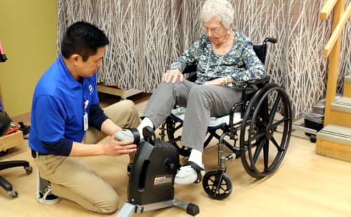 Director of Therapy, Gary Gumasing, working with short term rehabilitation patient with an exercise machine