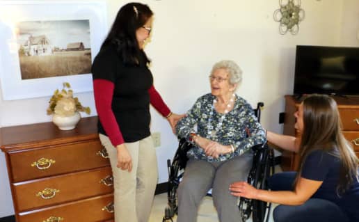 Two nurses speaking with an elderly patient